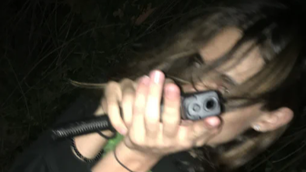 Scatto notturno di trenchmafia con un telefono in mano davanti al volto