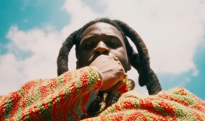 Denzel Curry in controluce contro il cielo, mano davanti alla bocca, scatto legato a ii