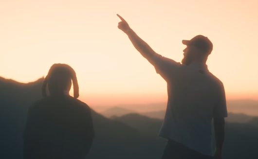 Denzel Curry e Kenny Beats al tramonto su un crinale: una indica l'orizzonte, scena legata a ii di Denzel Curry