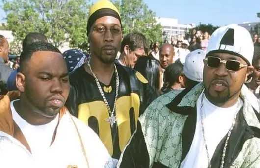 Tre membri dei Wu-Tang Clan all'aperto, in mezzo a un gruppo di persone