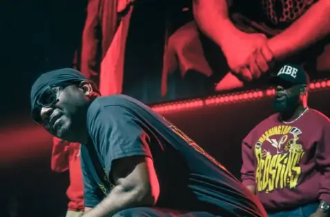 Un membro dei Wu-Tang Clan con occhiali e bandana sul palco durante un concerto